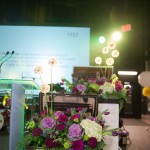 Staggered floral arrangements in briefcases, at different heights, flanked each side of the stage.